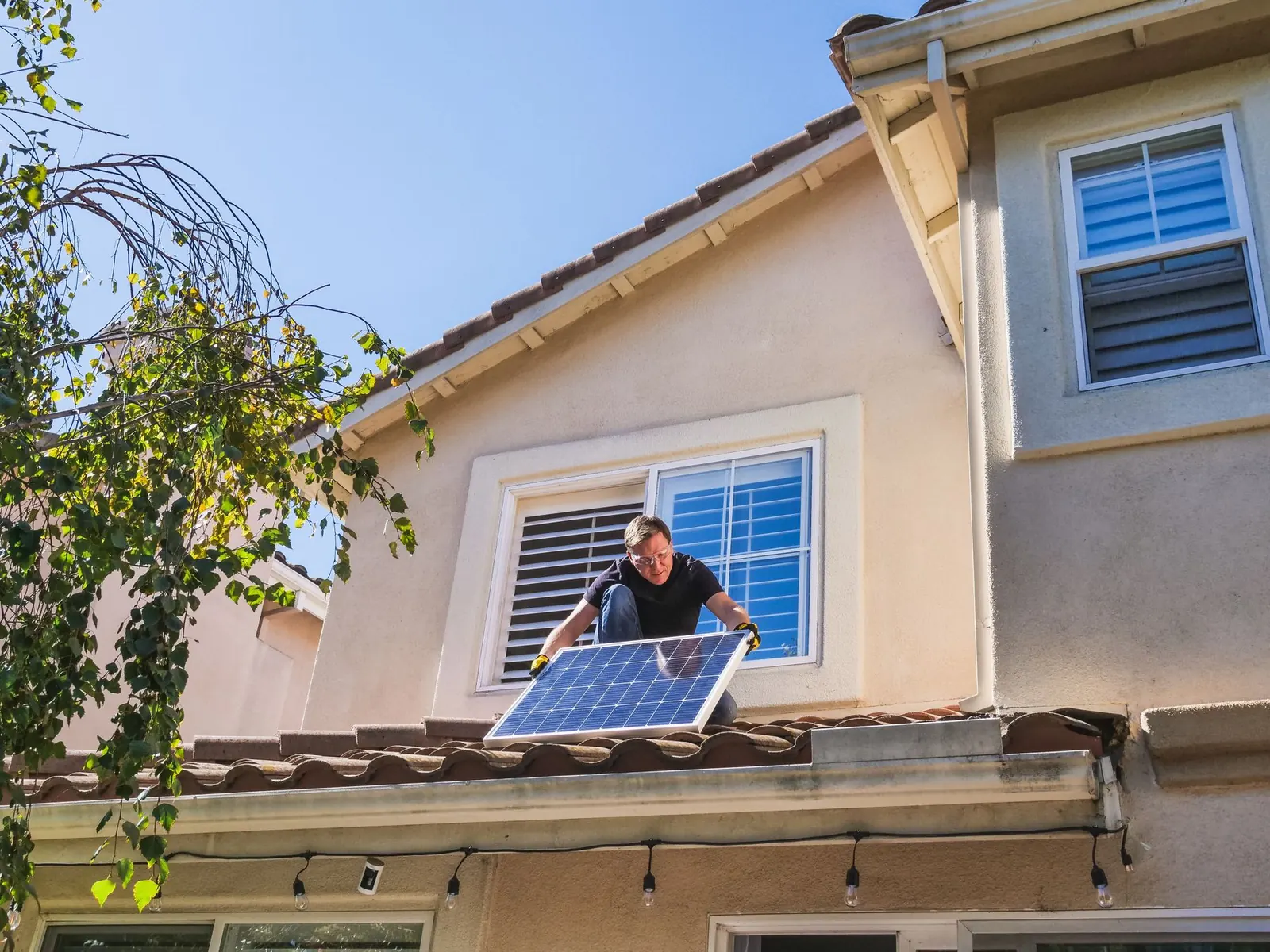 Solar technician servicing a panel on the tile roof of a stucco home in Escondido