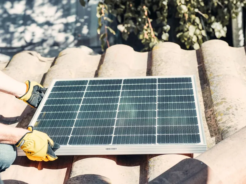 Technician inspecting a solar panel on a clay tile roof